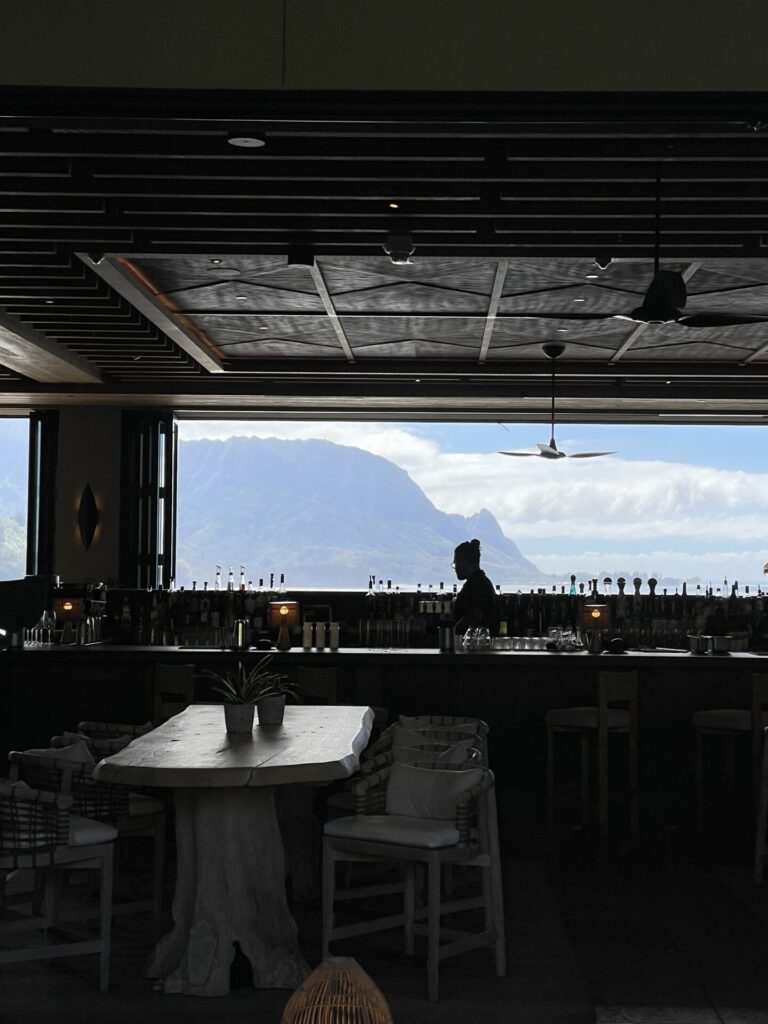bar at the 1 hotel Hanalei bay in silhouette with mountains and water through window