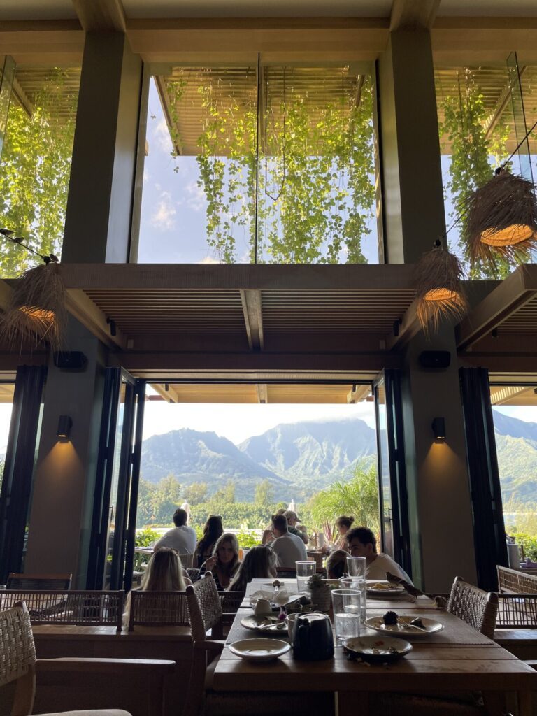 Breakfast views at the 1 Kitchen in Hanalei bay with green vines and mountains through large floor to ceiling windows