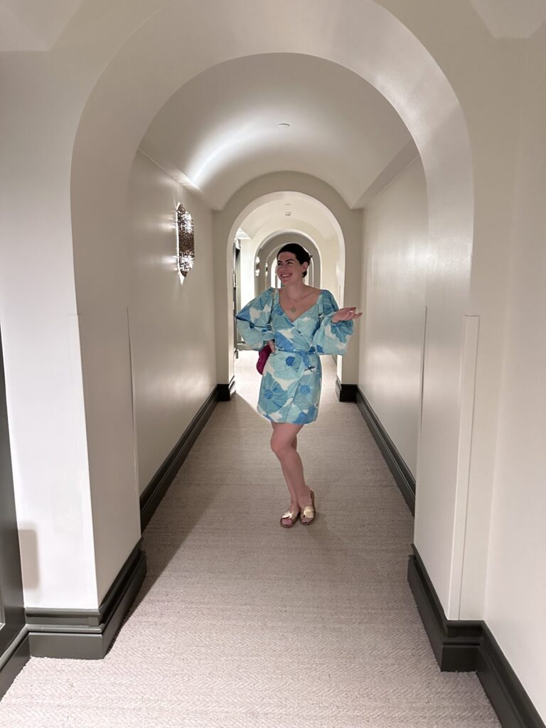 Natalie dressed for dinner in blue dress in white arched hallway of the 1 Hotel Hanalei Bay
