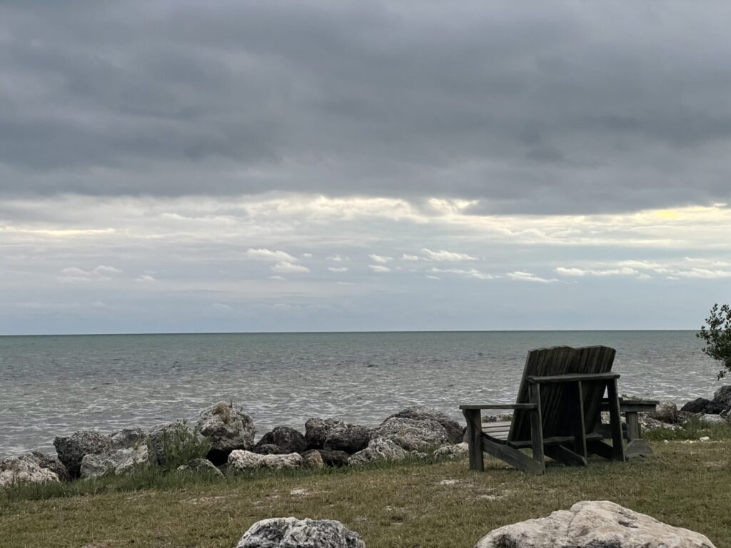 Adirondack chairs on long key state park beach with rocky coast and dark clouds